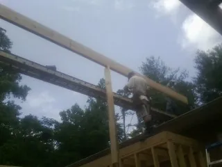Carpenter setting a ridge beam over a new addition frame — Ice Dam Removal by Roofing Brothers in Plush