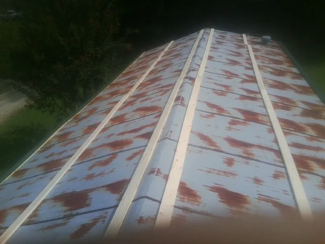 Rusted metal roof panels with new wood purlins before replacement — Storm Damage Roof Repair in Plush by Roofing Brothers