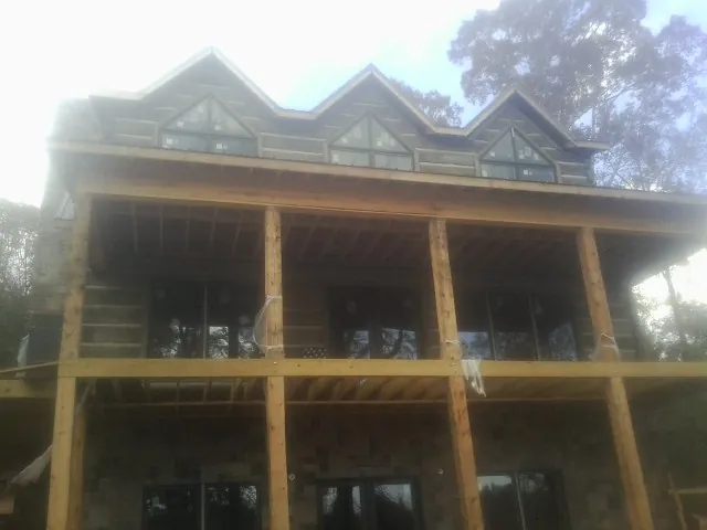 Dormers and porch framing on a large log home under construction — Roof Coating work by our crew in Plush
