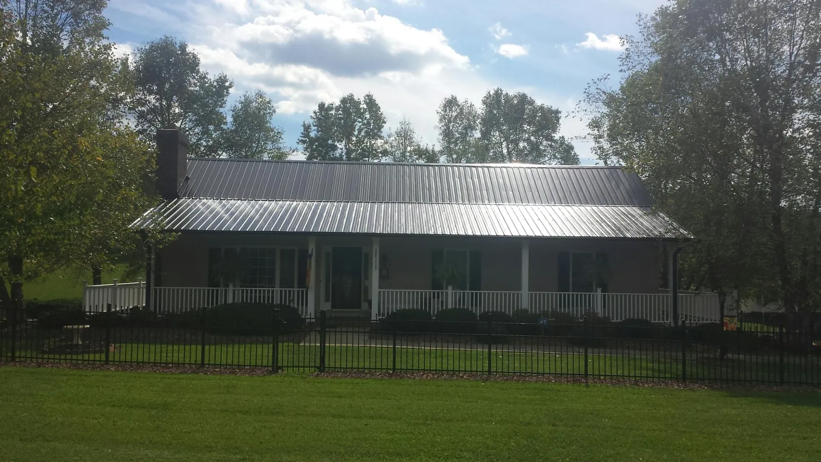Gray metal roof on a brick ranch with a full width front porch — Gutter Guard Installation work by our crew in Plush