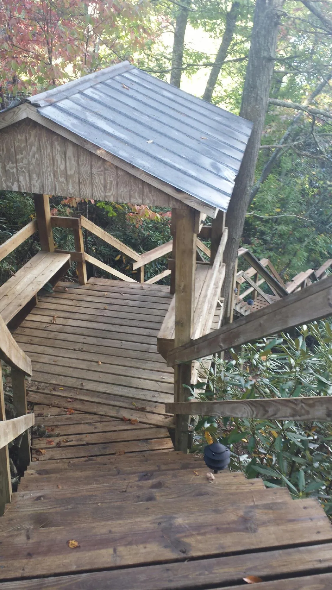 Metal roofed shelter over wooden steps on a wooded walkway — Skylight Repair & Installation work by our crew in Plush